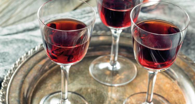 Trois verres de vin rouge sur un plateau.
