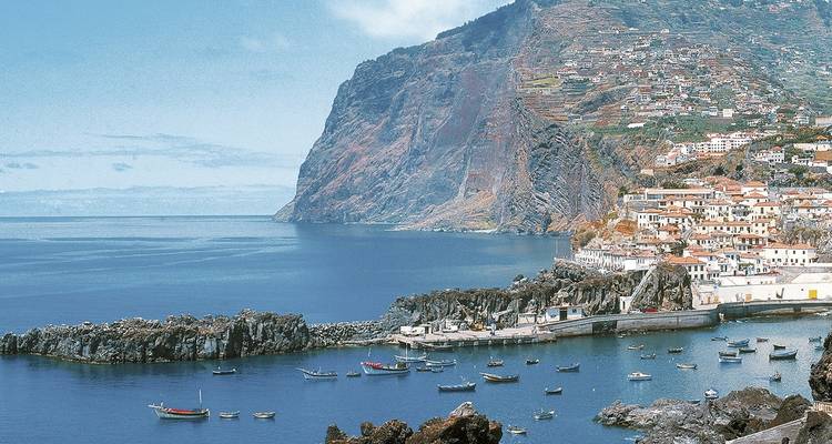 Vue côtière avec falaises, une ville et des bateaux sur l'eau.