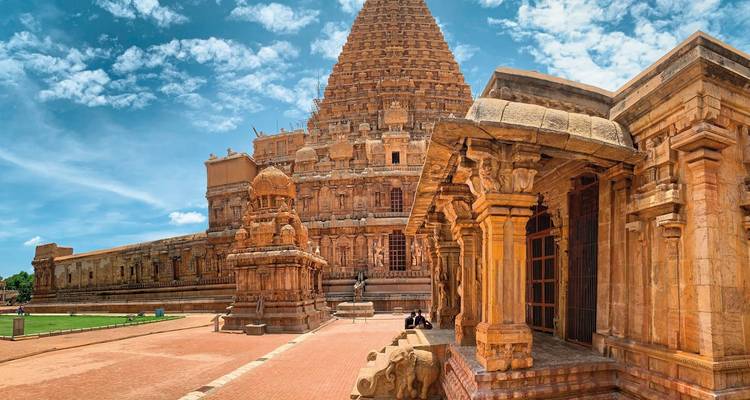 Großer antiker Tempel mit kunstvollen Schnitzereien und lebendiger Umgebung.