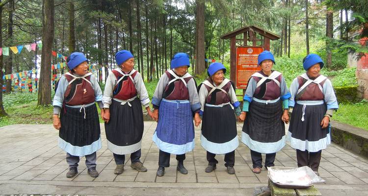 Group of people in traditional attire standing in a forest setting.