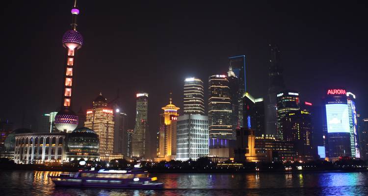 Iconische verlichte wolkenkrabbers van Shanghai's Pudong-district weerspiegeld op de rivier 's nachts.