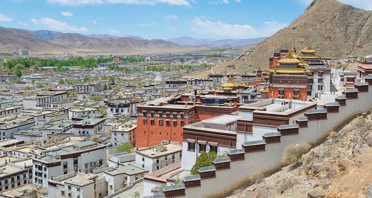 Vista de la ciudad de Shigatse con monasterios de cúpulas doradas y montañas.