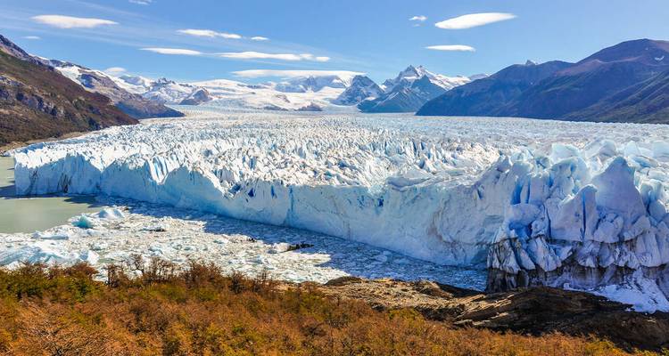 Wide view of a glacier with snowy mountains.
