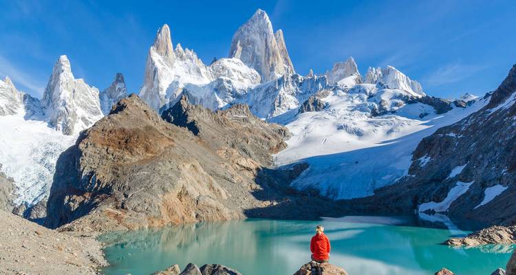 Person sitting by a lagoon with Mount Fitz Roy.