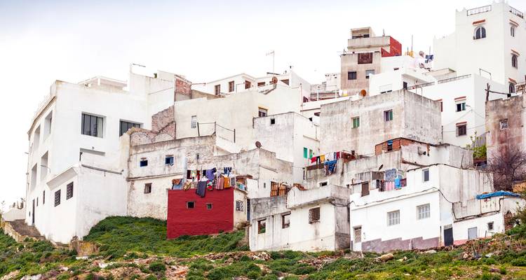 Ladera escalonada de casas de hormigón blanco con parches de vegetación y ropa colgada.