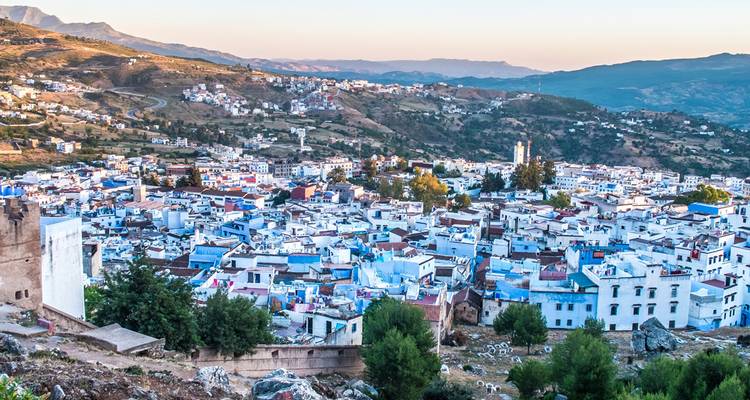Las viviendas azules y blancas de Chefchaouen cubren el valle bajo las montañas lejanas al amanecer.