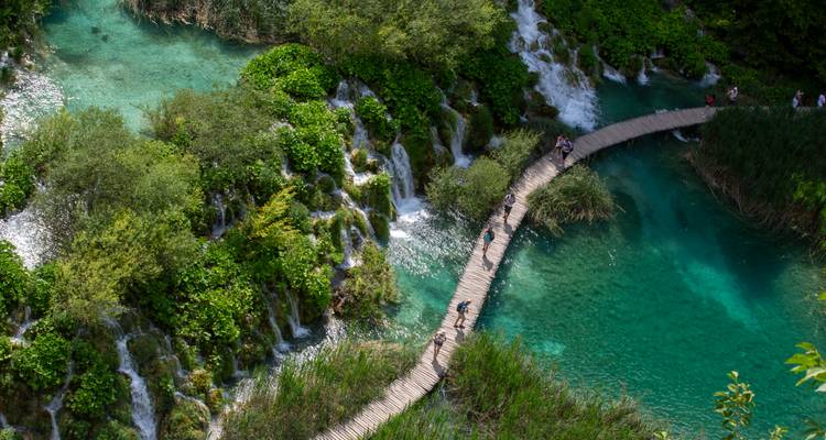 Vue aérienne de la passerelle en bois sinuant sur des bassins d'émeraude et des cascades dégringolant aux lacs de Plitvice