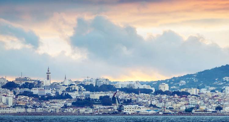 Coastal skyline of Tangier at dawn with colorful clouds over the city and harbor