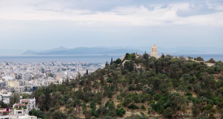 Aerial view of a city with greenery and distant mountains.