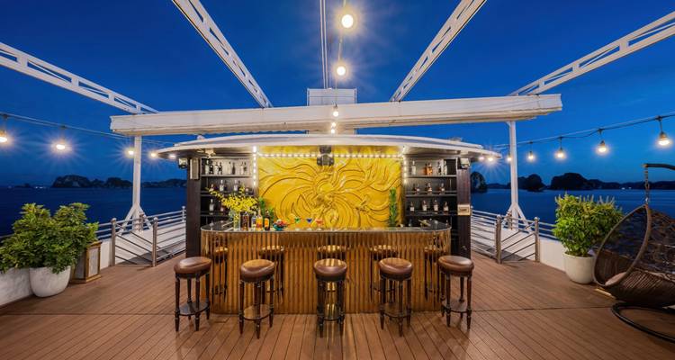 Een cruiseschip bar 's nachts met barkrukken en decoratieve verlichting.