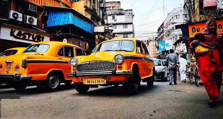 Yellow taxis and rickshaw on a bustling street.
