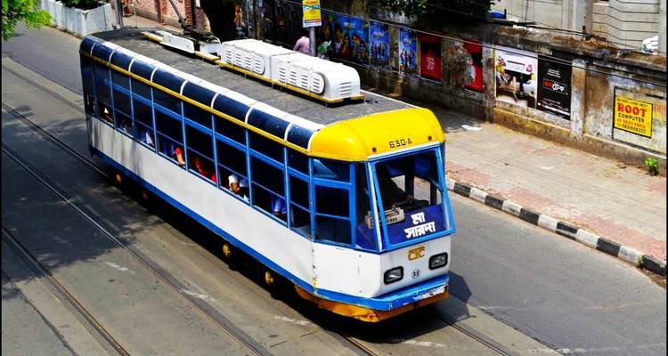 Blue and yellow tram moving along tracks in a city.