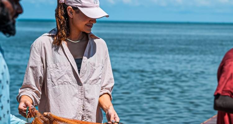 Person holding a fishing net by the sea.