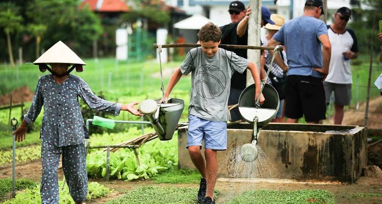 A local and a child watering plants in a vegetable garden