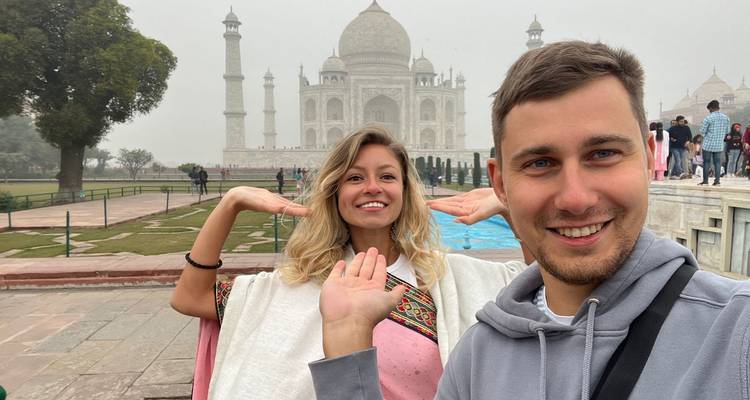 Couple smiling in front of the Taj Mahal.