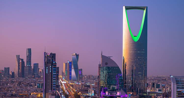 Riad-Skyline in der Abenddämmerung mit dem beleuchteten Kingdom Centre Tower, der grün leuchtet.