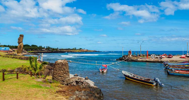 Haven met Moai-standbeeld en boten op zee op een zonnige dag.