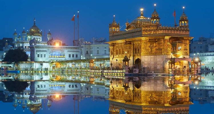 Temple d'Or illuminé la nuit à Amritsar se reflétant dans un bassin.