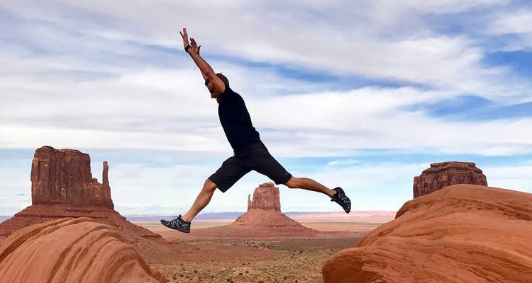 Viajero saltando entre formaciones de arenisca en Monument Valley