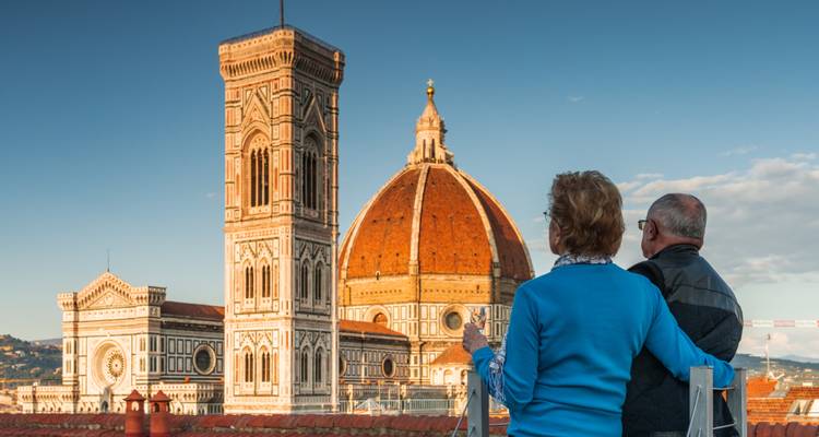 Un couple de personnes âgées admire le Duomo et le Campanile de Giotto depuis une terrasse sur le toit à Florence.