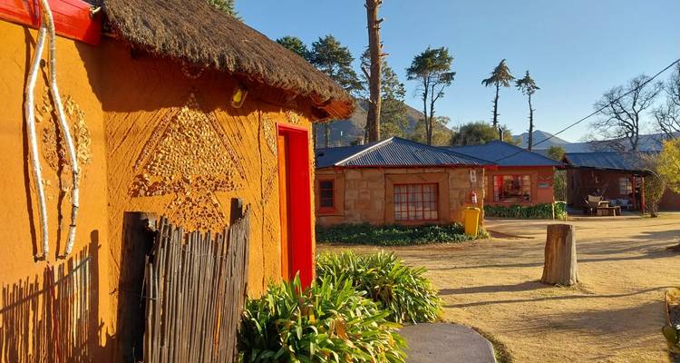 Kleurrijke adobe-stijl gebouwen met rode afwerking en helder zonlicht in een landelijke dorpsomgeving.