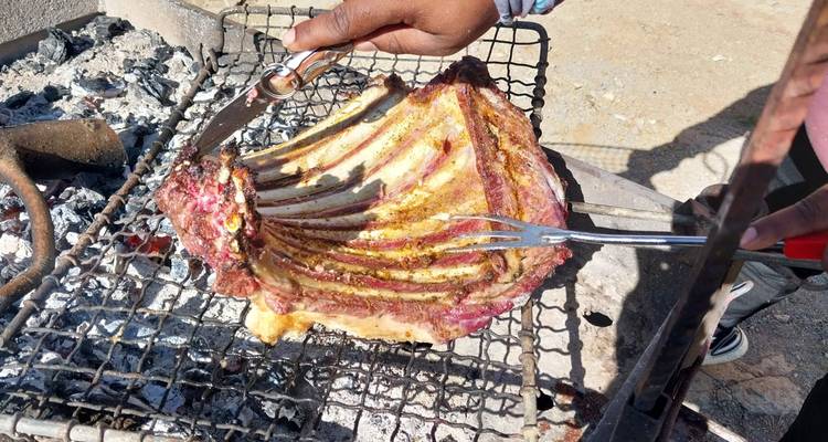 Close-up van ribben die garen op een metalen grill boven hete kolen.