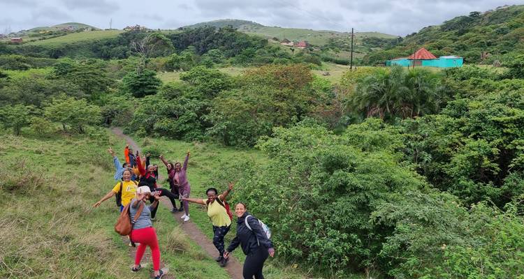 Vrolijke groep wandelaars die over een smal pad door weelderige groene heuvels loopt.