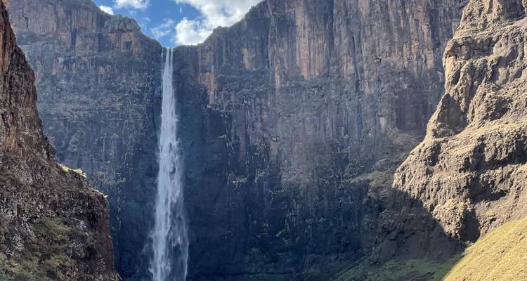 Hoge, smalle waterval die naar beneden stort langs een steile basaltwand in een schaduwrijke kloof.