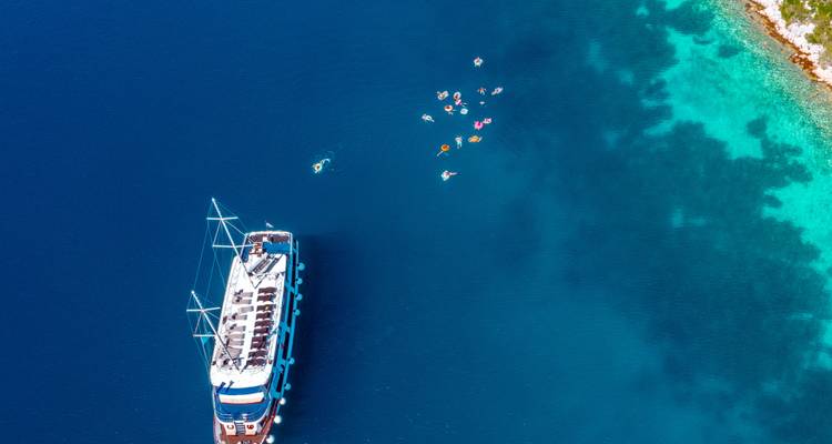 Luftaufnahme einer Yacht mit Menschen, die in der Nähe schwimmen.