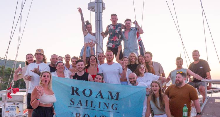 Gruppenfoto von Menschen auf einem Boot mit einem Roam Sailing Banner.