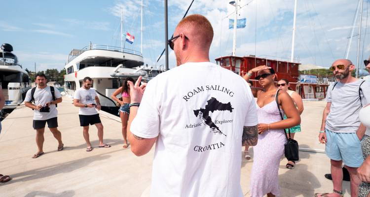 Gruppe von Menschen auf einem Steg in der Nähe von Yachten.