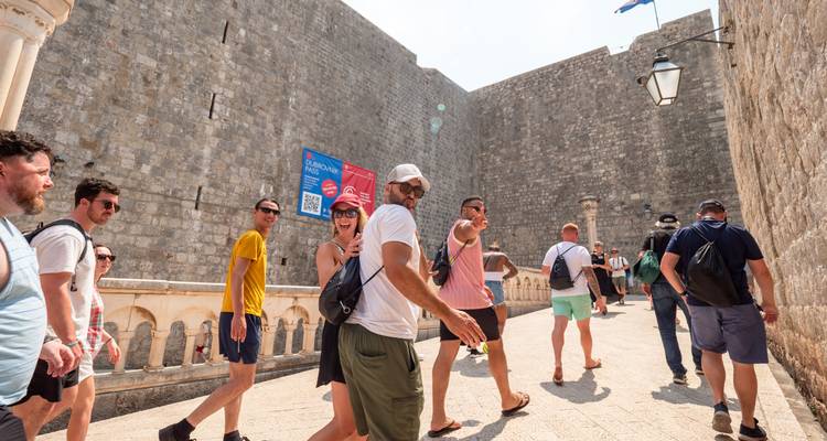 Touristen, die in der Nähe alter Steinmauern spazieren gehen.