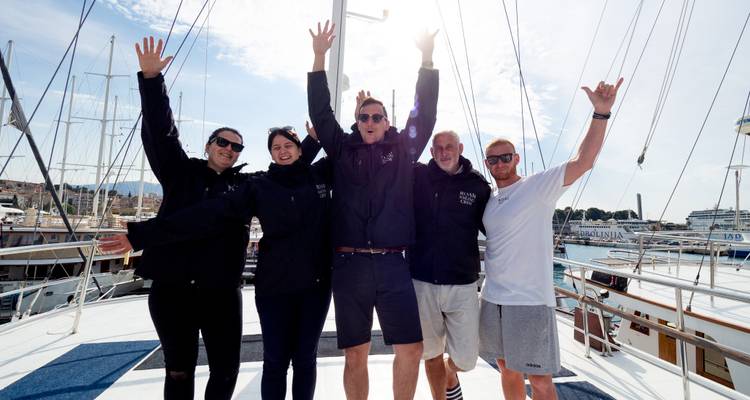 Menschen posieren auf einem Boot mit erhobenen Armen.