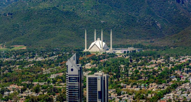 Vue aérienne de la ville d'Islamabad encadrée par les vertes collines de Margalla avec la mosquée blanche Faisal en évidence au centre
