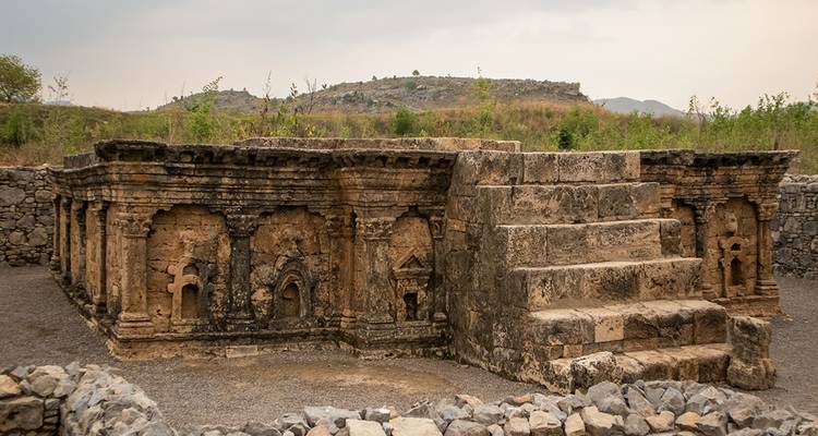 Fondations en pierre patinée et plateforme à degrés d'un ancien monastère bouddhiste entouré de collines basses