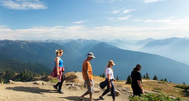 Groupe de randonneurs marchant le long d'une crête avec des montagnes en arrière-plan.