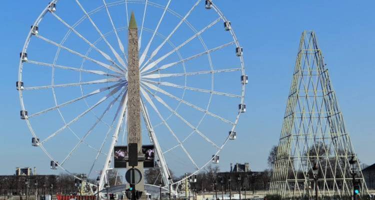Grande roue géante près d'une structure ressemblant à un obélisque.