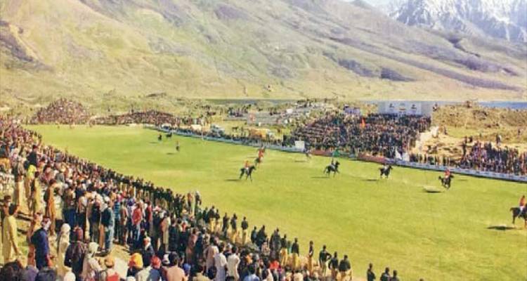 Vue panoramique de spectateurs bordant un terrain de polo de montagne sous un ciel partiellement nuageux.
