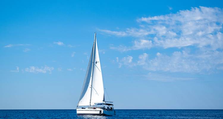 Zeilboot op de open zee onder een heldere blauwe lucht.