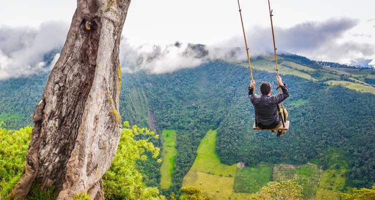 Eine Person auf einer Schaukel mit Blick auf üppig grüne Berge.