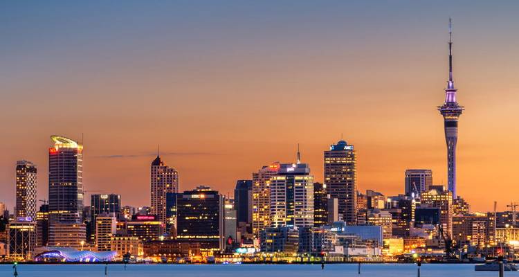 Horizon urbain au coucher du soleil avec bâtiments illuminés et tour du ciel.