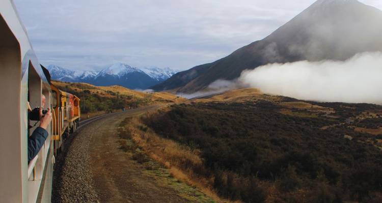 Train sur une voie sinueuse à travers un terrain montagneux.