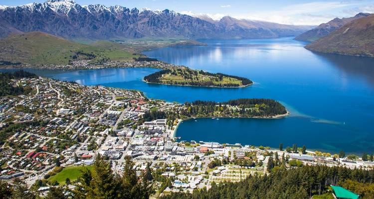 Vue aérienne d'une ville au bord d'un lac avec des montagnes environnantes.