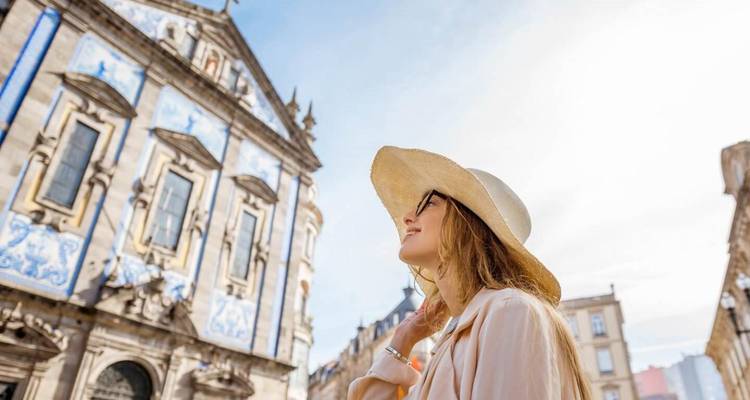 Jonge vrouw met een strohoed die op een heldere dag een sierlijke kerkgevel met blauwe tegels bewondert