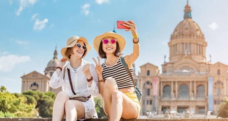 Twee vrolijke vrienden die een selfie maken met het sierlijke koepelvormige Nationale Paleis van Barcelona op de achtergrond