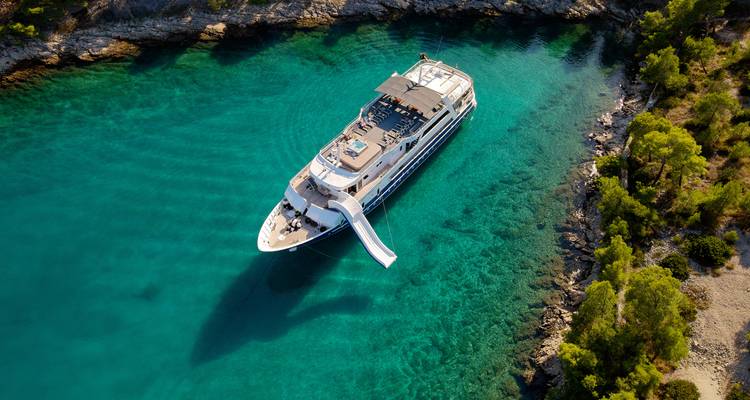 Luxury yacht in clear turquoise waters along a rocky coastline
