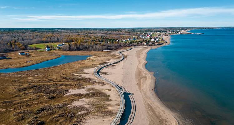 Ein langer Sandstrand mit Meerblick unter blauem Himmel.