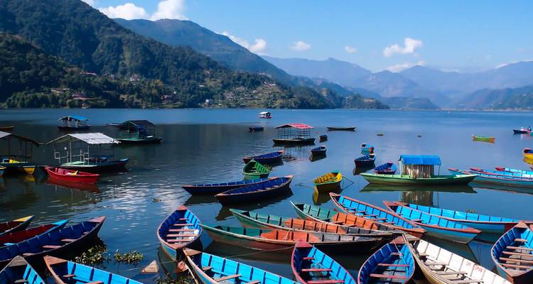 Bateaux colorés sur un lac à Pokhara entouré de collines.
