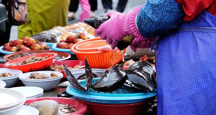 Vendor preparing fresh seafood at a local market.