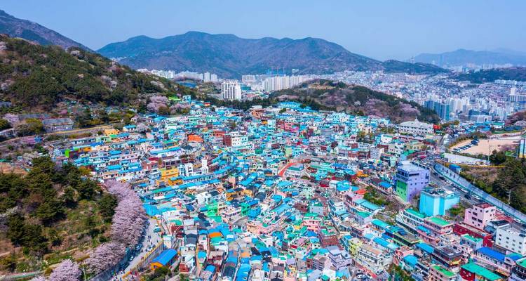 Colorful hillside village with numerous small houses and a mountainous backdrop.